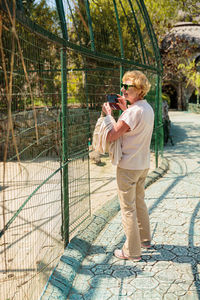 Elderly woman with mobile smartphone taking photo in zoo