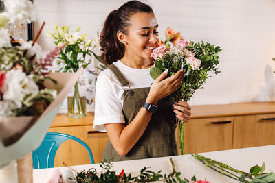 Smiling female florist holding bouquet in shop