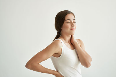 Beautiful young woman standing against white background