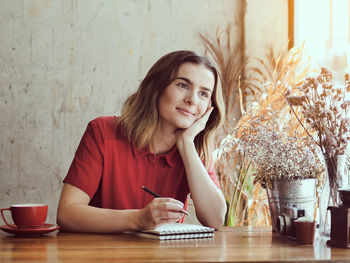 Portrait of a smiling young woman sitting on table