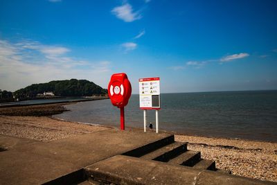 Road sign by sea against sky