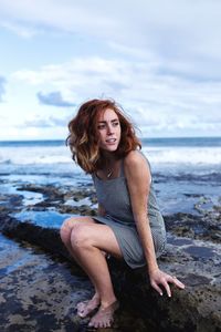 Portrait of smiling young woman on beach against sky