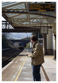 Side view of man standing at railroad station