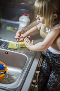 Midsection of baby girl holding water in kitchen