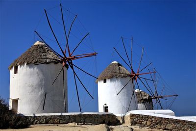 Low angle view of traditional windmill on field against clear blue sky