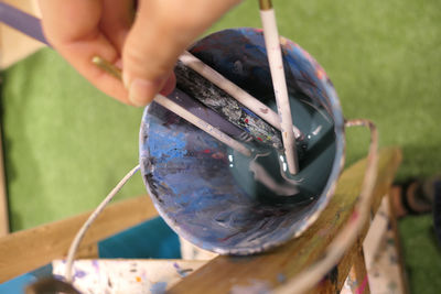 Cropped hand of person holding paintbrush in container