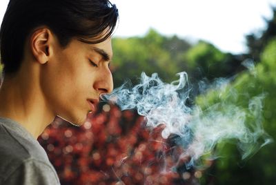 Side view of young man smoking outdoors