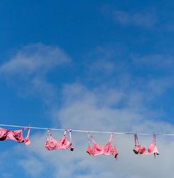 Low angle view of bras hanging on clothesline against sky