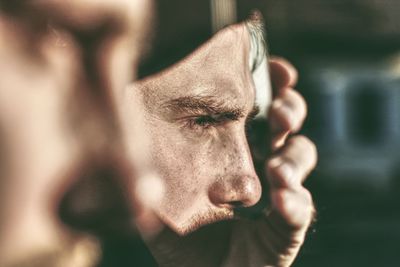 Close-up of man holding broken mirror outdoors