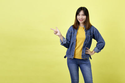 Portrait of smiling young woman against yellow background