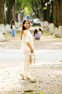 Portrait of young woman walking on road