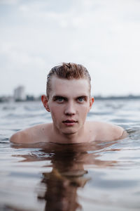 Portrait of shirtless man in sea against sky