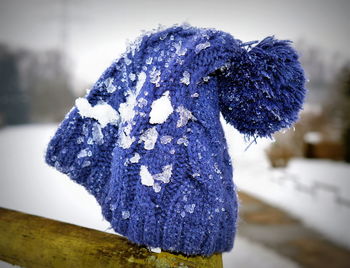 Close-up of knit hat with snow on fence