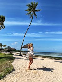 Woman standing at beach against sky