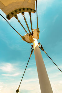 Low angle view of electric lamp hanging against sky