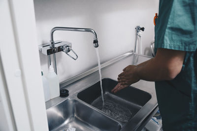Cropped image of male nurse washing hands in sink at hospital