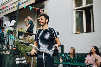 Smiling young man standing with bicycle in backyard