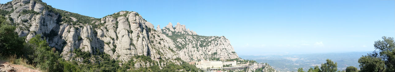 Panoramic view of rocky mountains against clear sky