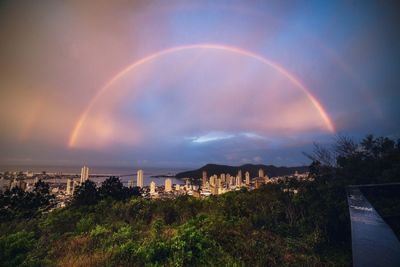 Rainbow over buildings in city against sky