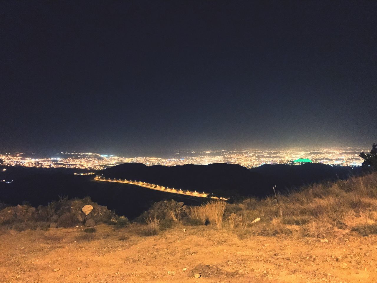 ILLUMINATED ARCH BRIDGE OVER RIVER AGAINST SKY AT NIGHT