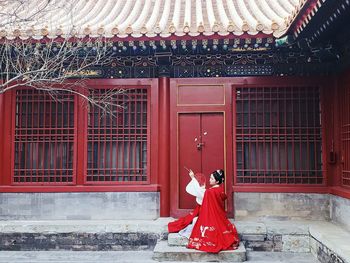 Woman standing against red building