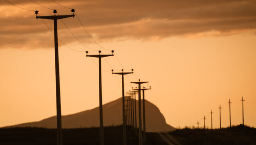 Low angle view of silhouette electricity pylon against sky during sunset