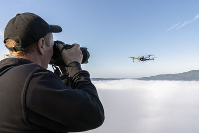 Midsection of man photographing against sky