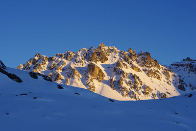 Scenic view of snowcapped mountains against clear blue sky