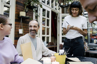 Smiling owner taking order of family at restaurant