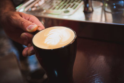 Cropped hand of man holding coffee on table