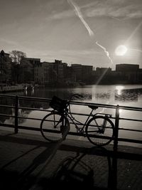 Bicycle by railing against buildings in city