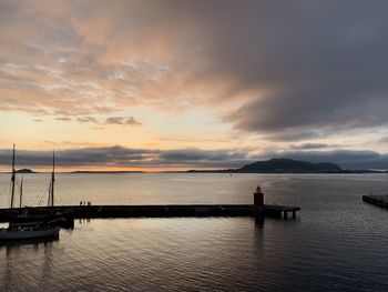 Aerial view of a harbor and a peer at sunset with horizon over the sea and dramatic sky 