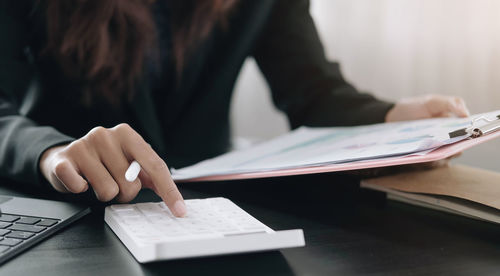 Midsection of woman reading book on table