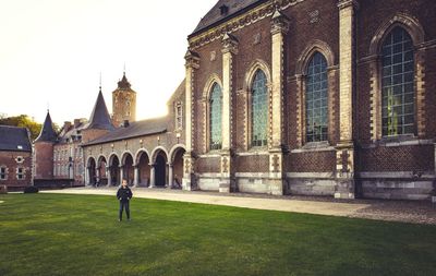 Full length of boy standing on grass against church 