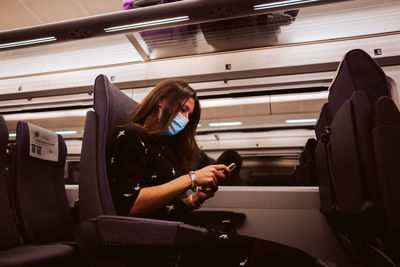 Young woman using mobile phone while sitting in bus