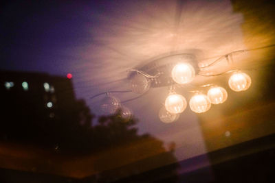 Low angle view of illuminated lights against sky at night