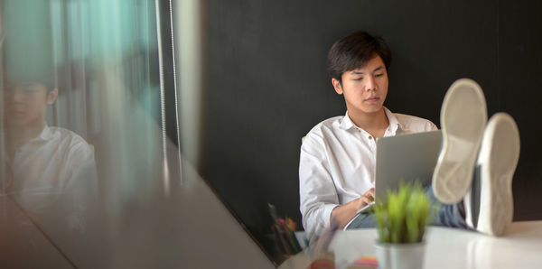 Young man using mobile phone while sitting on table