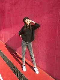 Portrait of a smiling young woman standing against red wall