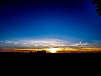 Silhouette landscape against blue sky at sunset