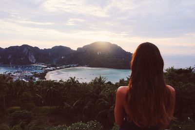 Woman looking at sea against sky during sunset