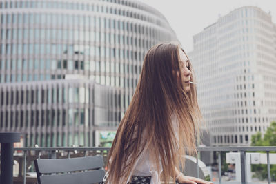 Woman with lollipop in mouth while sitting in city