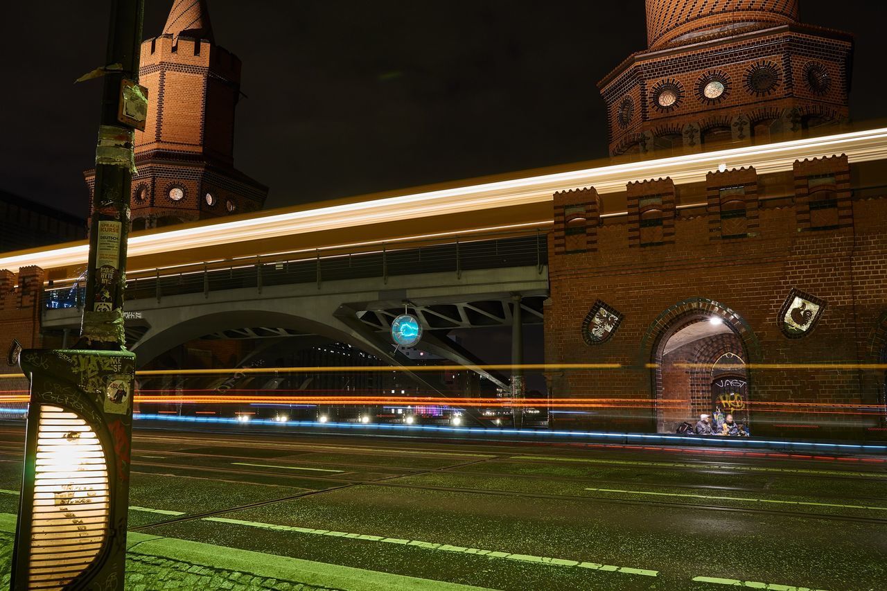 LIGHT TRAILS ON ROAD AGAINST BRIDGE AT NIGHT