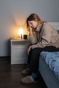 Cute girl sitting on bed and holding her head. woman suffering from headache or migraine.