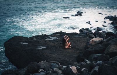 High angle view of naked woman sitting at beach