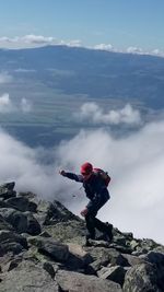 Man standing on rock against sky