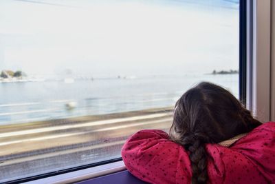 Rear view of woman looking through window