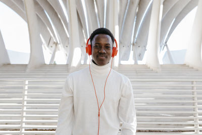 Smiling young man wearing orange colored headphones