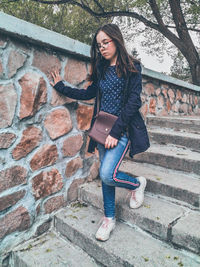 Full length of woman standing against brick wall