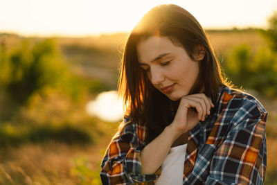 Woman closed her eyes, praying in a field during beautiful sunset.