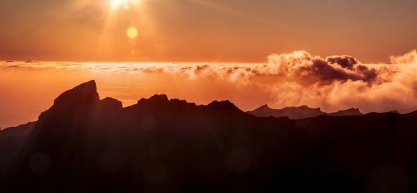 Above the clouds and mountain peaks.  silhouette of peaks, clouds and rays of the sun on teneriffe.